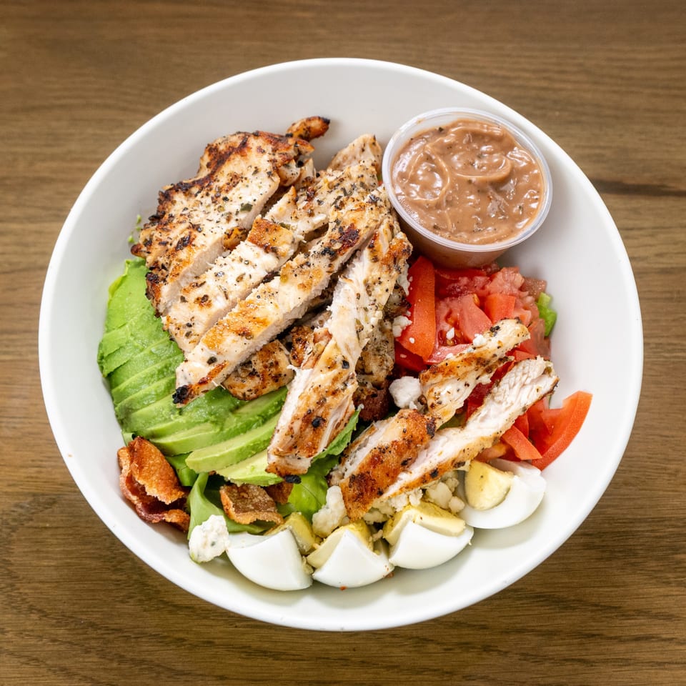 A P'unk Burger grilled chicken salad with avocado, tomatoes, eggs, bacon, and dressing.